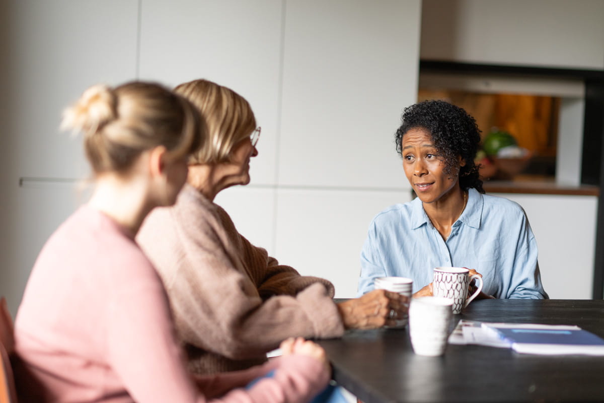 Trois personnes sont réunies autour d'une table pour discuter.