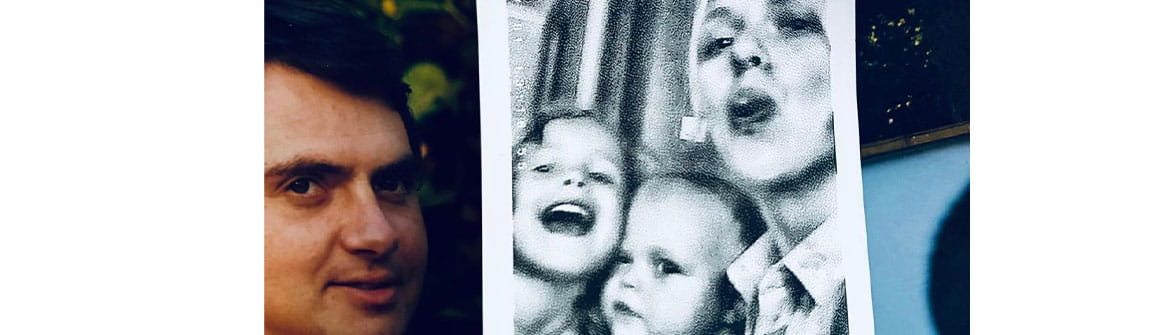 Gros plan de plusieurs photos de famille imprimées. Au centre, une photo en noir et blanc montre un adulte tenant deux jeunes enfants dans les bras. À gauche, un portrait séparé est visible. Les photos sont disposées côte à côte et évoquent les souvenirs et les liens affectifs.
