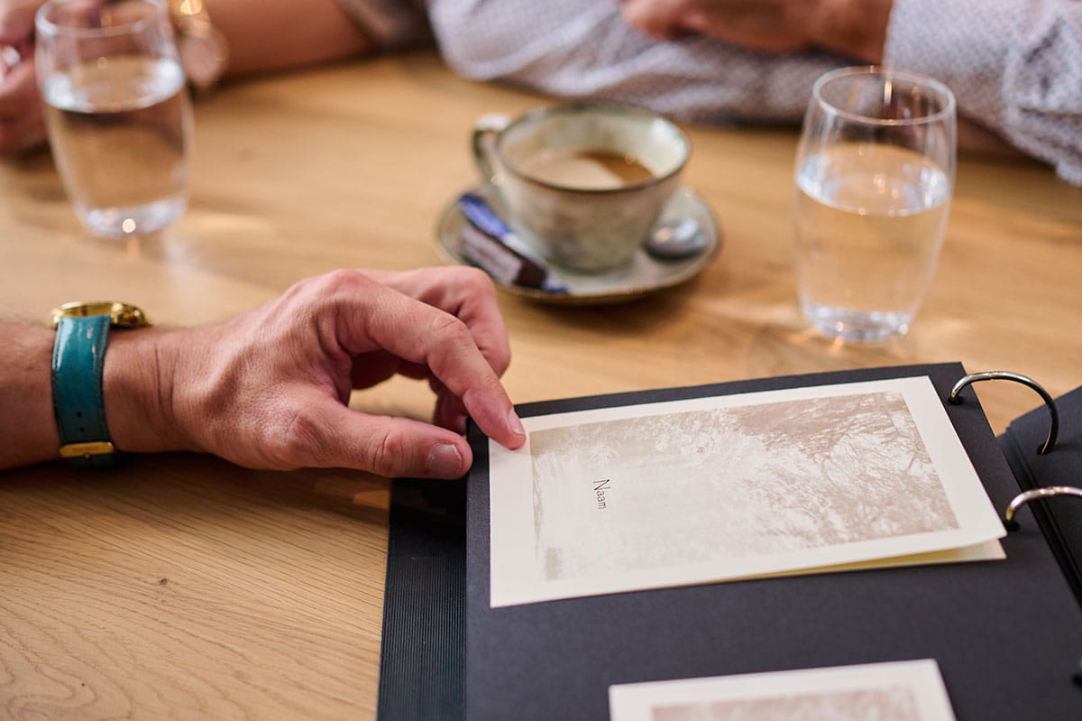 Une personne examine une carte commémorative dans un classeur lors d’un entretien à table.